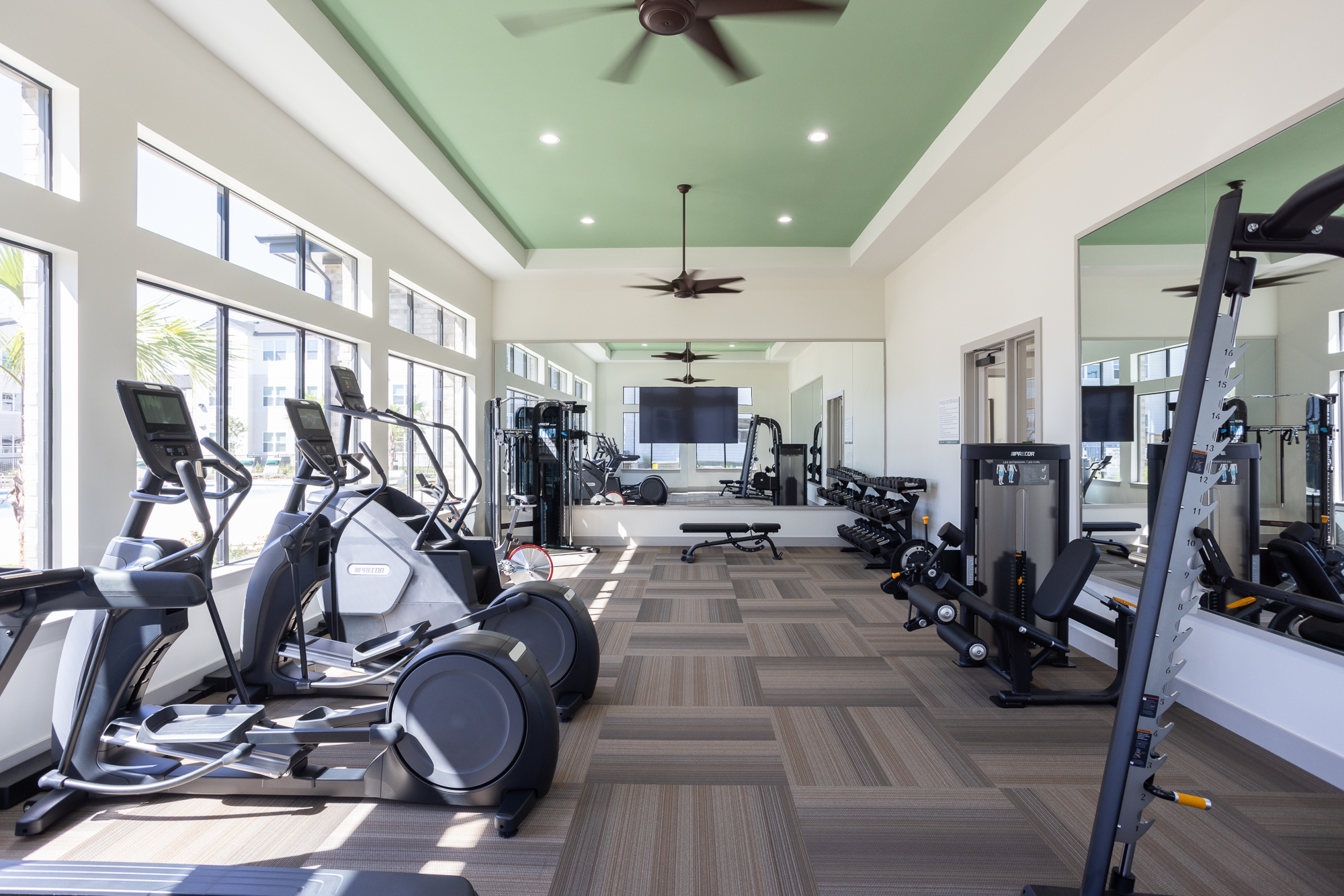 Bright fitness center with cardio machines, weightlifting equipment, and large mirrors at Prose Thunder ROck in Marble Falls, TX