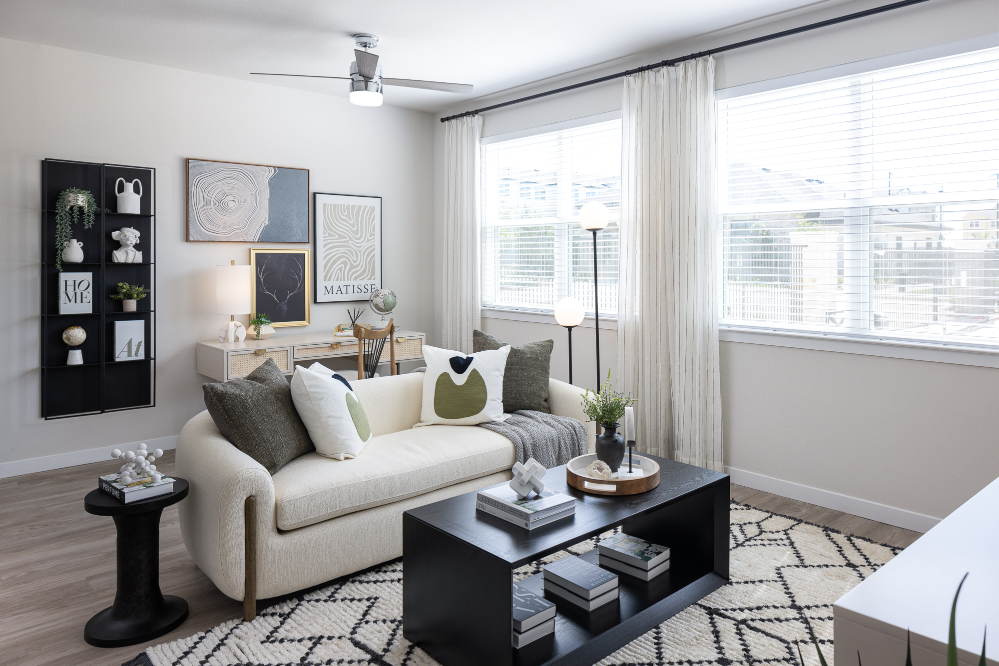 Cozy living room with a white sofa, black coffee table, wall art, and large windows with blinds at Prose Thunder Rock in Marble Falls, TX.