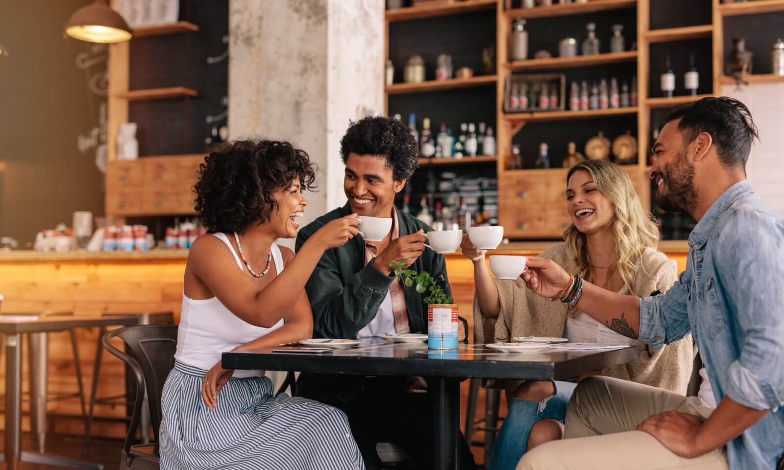 Young people sitting at cafe table and having coffee together.