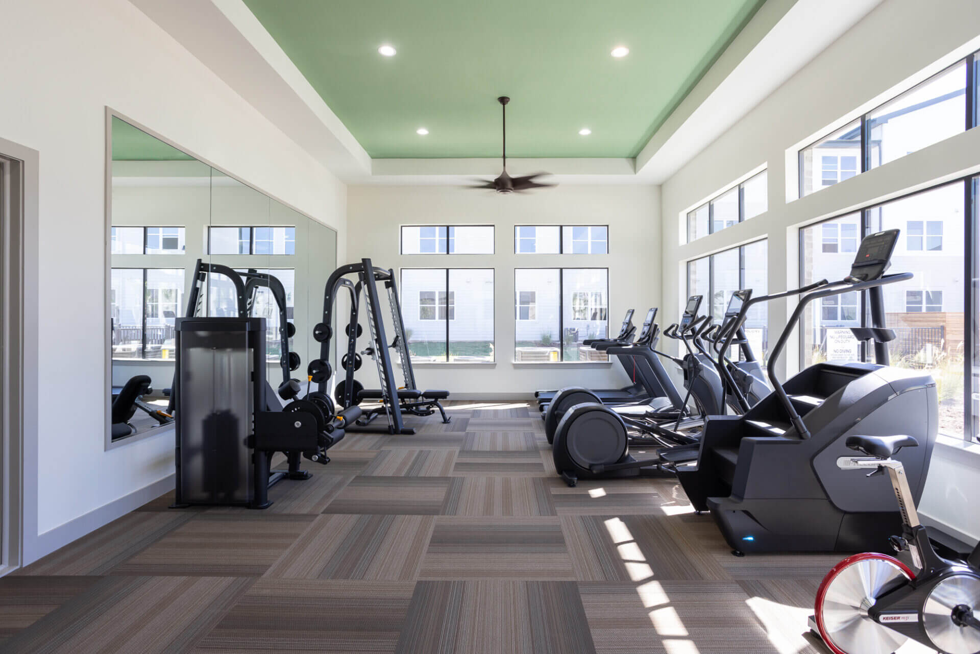 Bright fitness center with cardio machines, weightlifting equipment, and large mirrors at Prose Thunder Rock in Marble Falls, TX