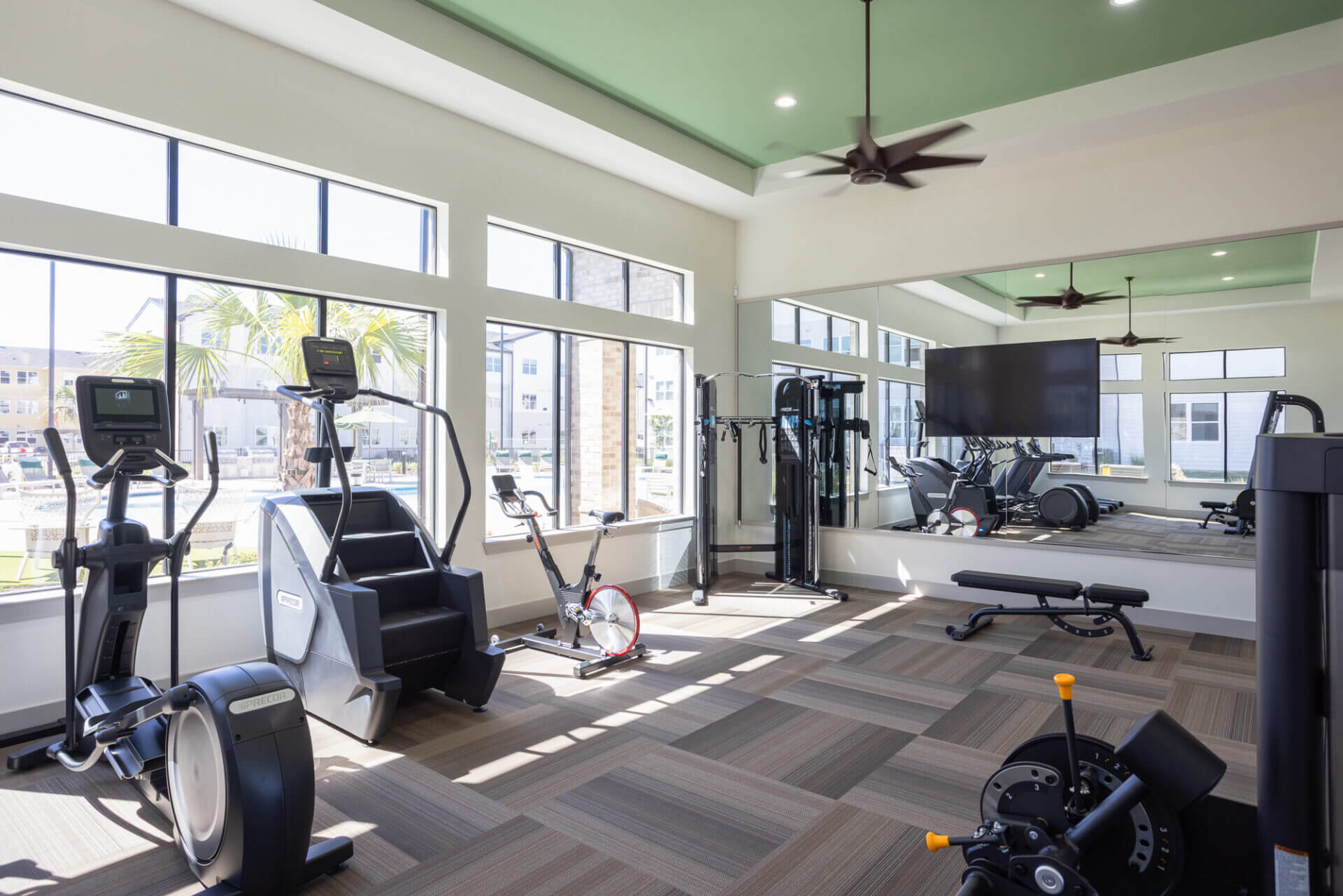 Bright fitness center with cardio machines, weightlifting equipment, and large mirrors at Prose Thunder Rock in Marble Falls, TX