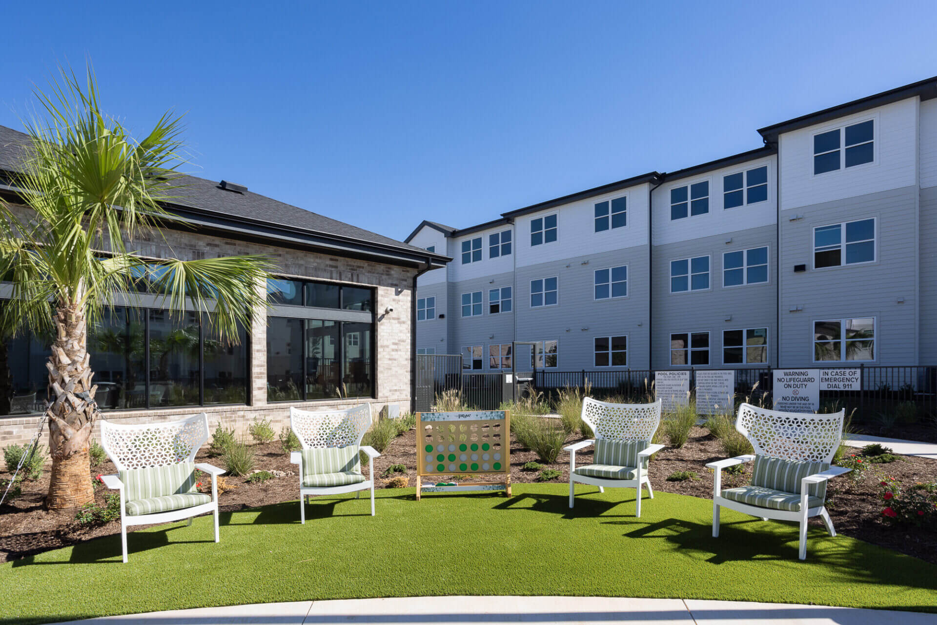 A group of lawn chairs sitting on top of a lush green field turf with games nearby